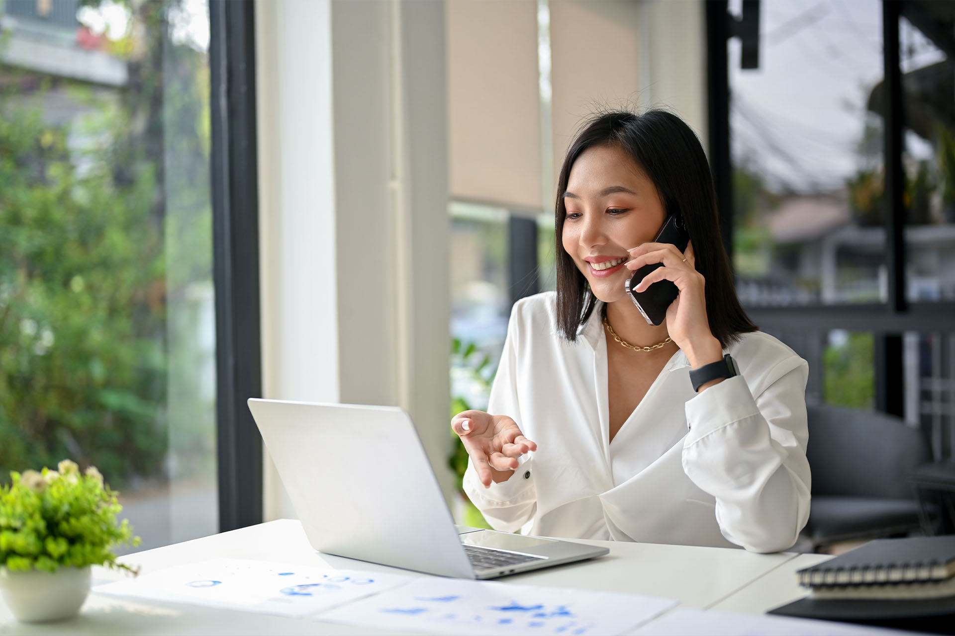 young woman talking on the phone and pointing at her laptop
